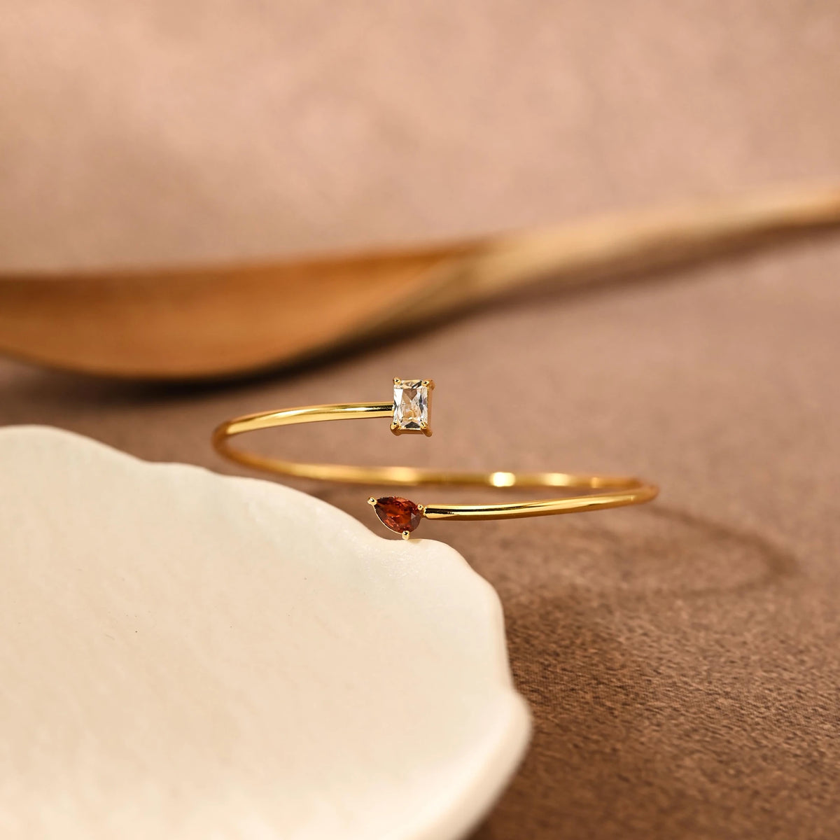 Side view of the open gold-tone bangle and crystal settings