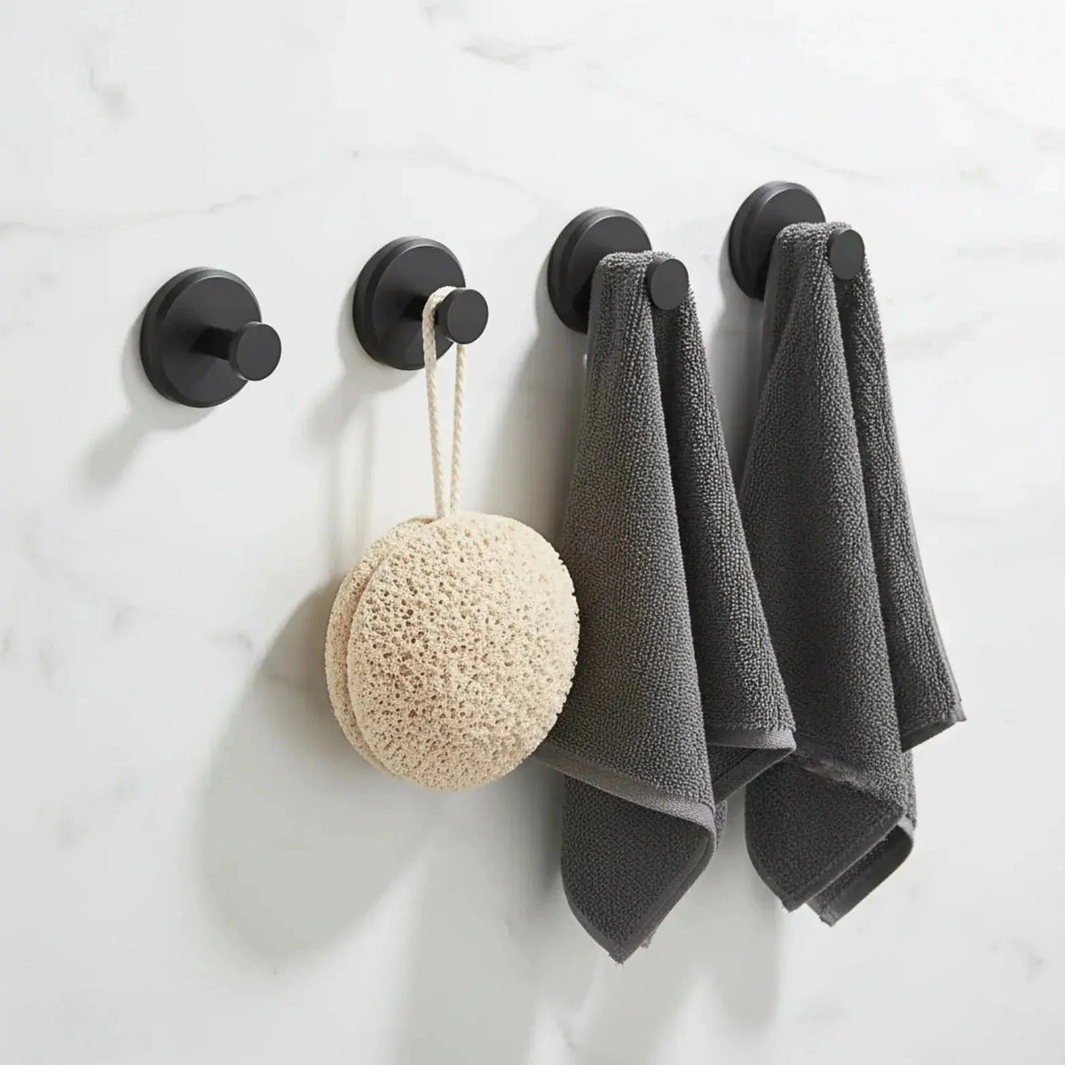 Set of four black suction cup hooks holding towels and bathroom accessories