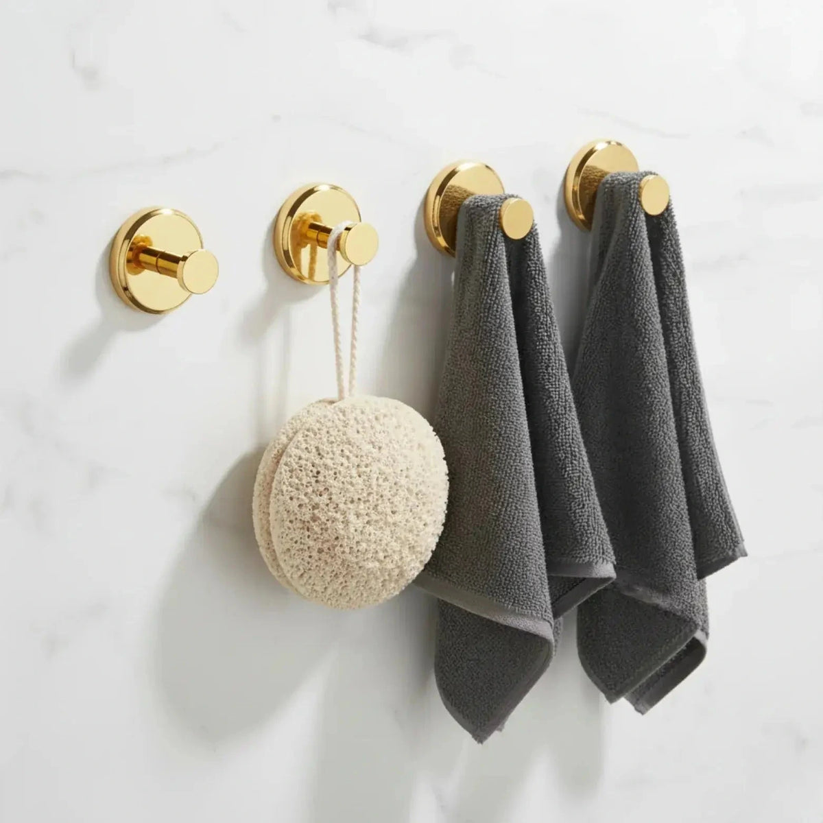 Set of four polished gold suction cup hooks shown on a bathroom wall