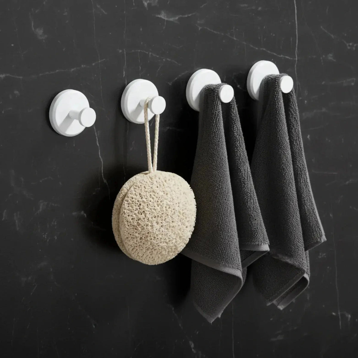 Set of four white suction cup hooks shown on a bathroom wall