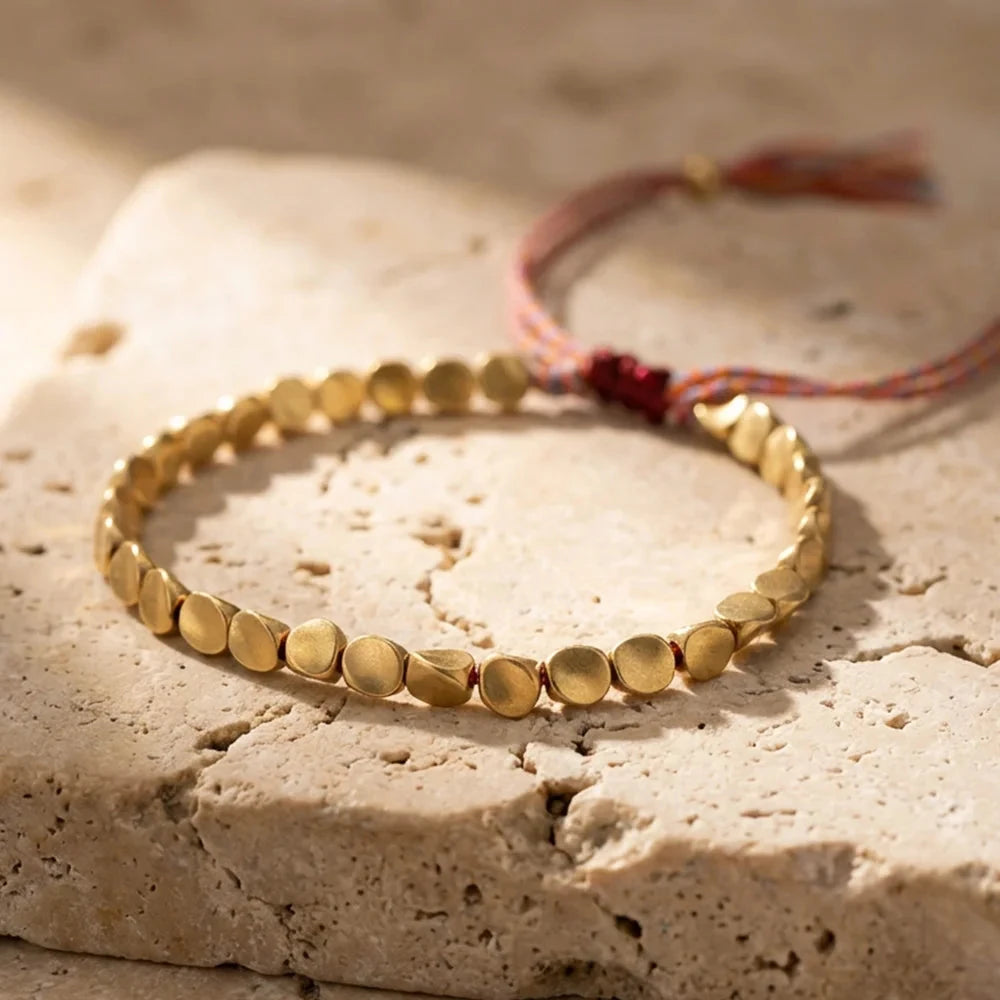 Full bracelet showing the warm metal beads and braided sliding cord